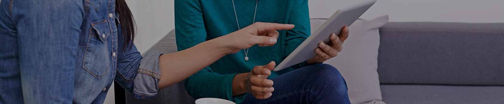 two women sitting, reviewing papers that one of the women is holding