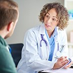 Female health care provider sitting at a desk, talking seriously with a person