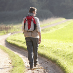 A lone individual walking along a lonely road looking into the distance